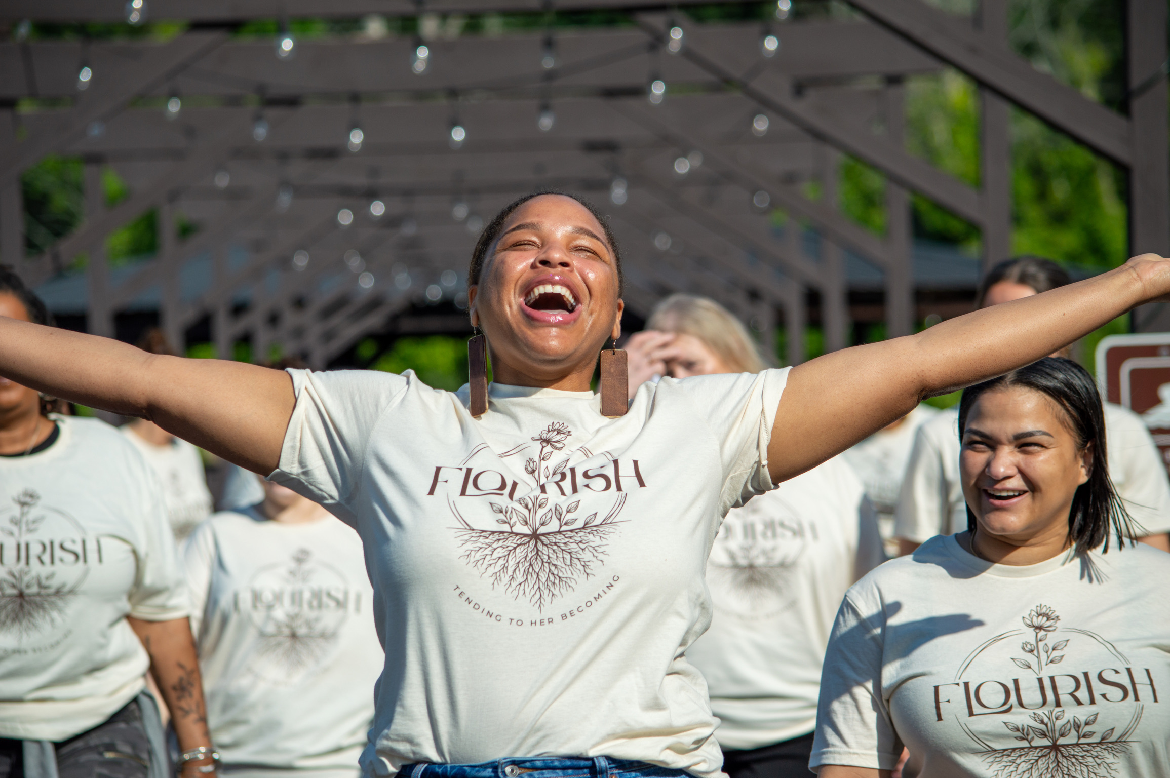 A woman in a Flourish shirt with arms open wide, laughing with joy