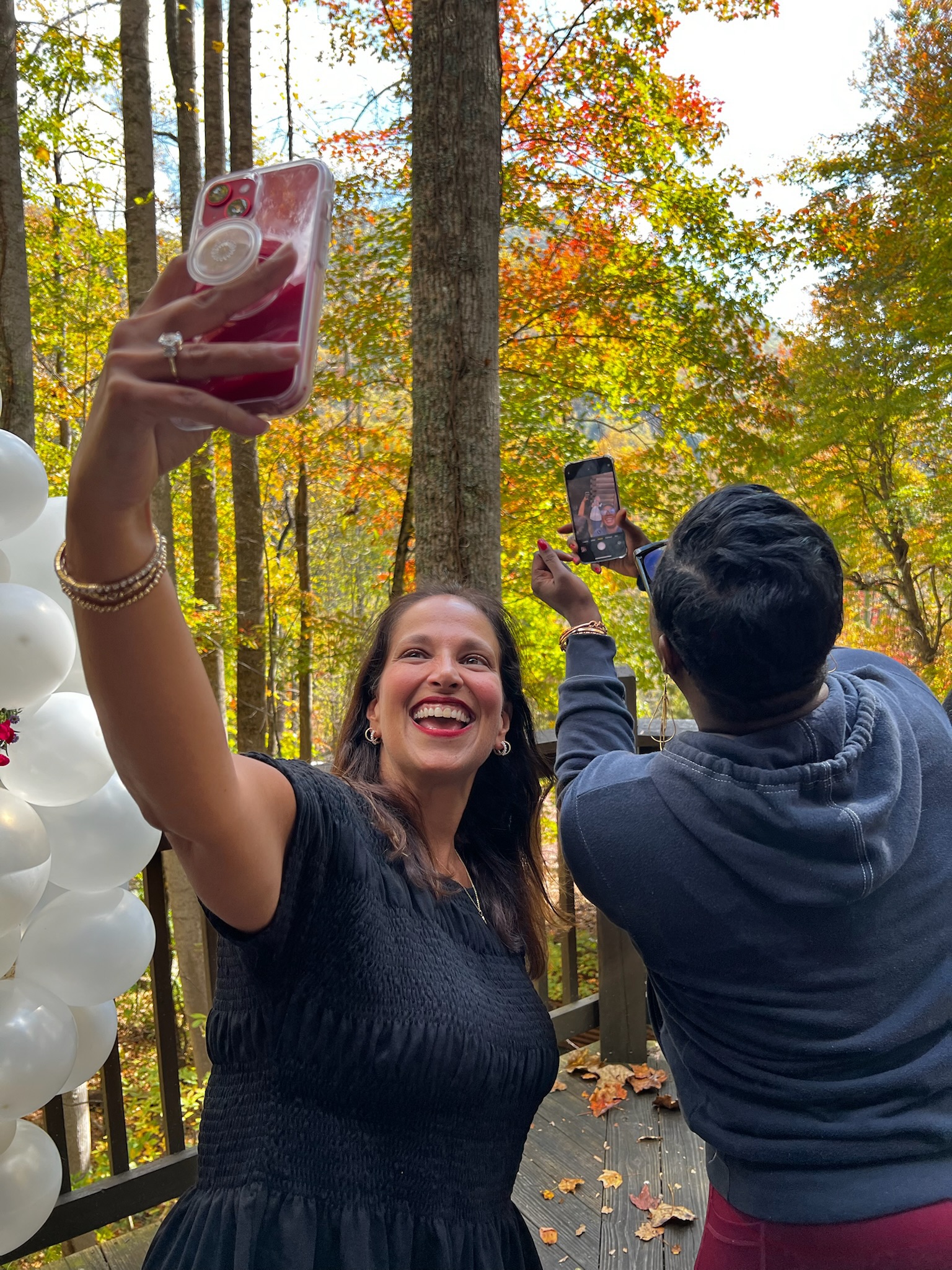 Women taking selfies among autumn trees