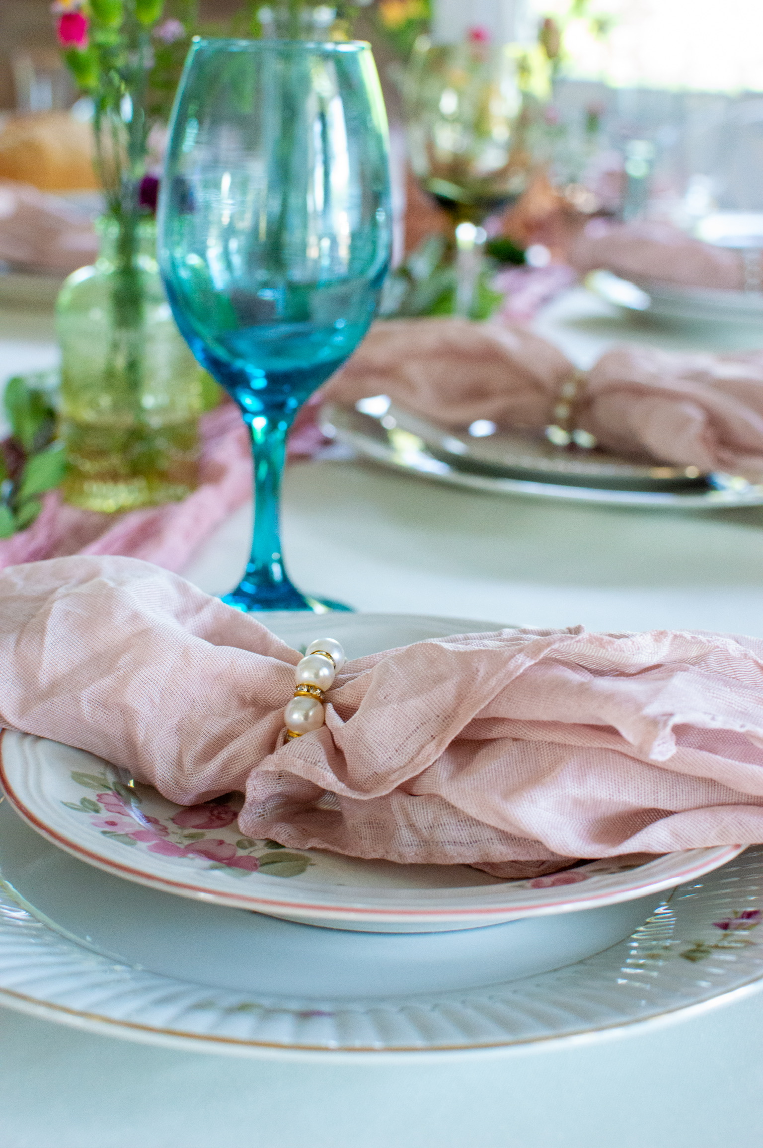A blush napkin with a pearl ring on floral china