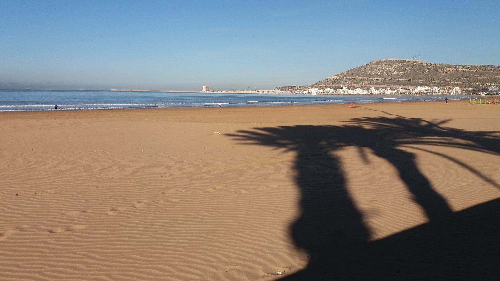 Agadir crescent beach with Agadir Oufella hill behind, day, solid blue sky