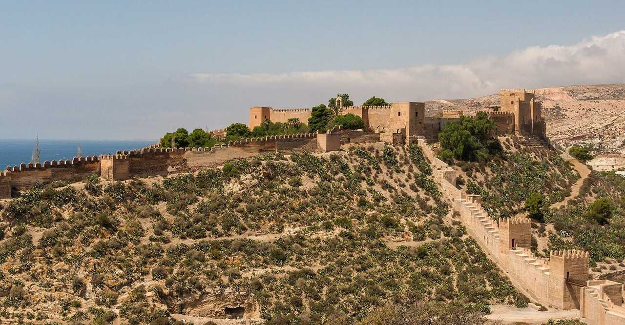 Alcazaba of Almeria on the hillside with Mediterranean beyond, day, pale blue sky