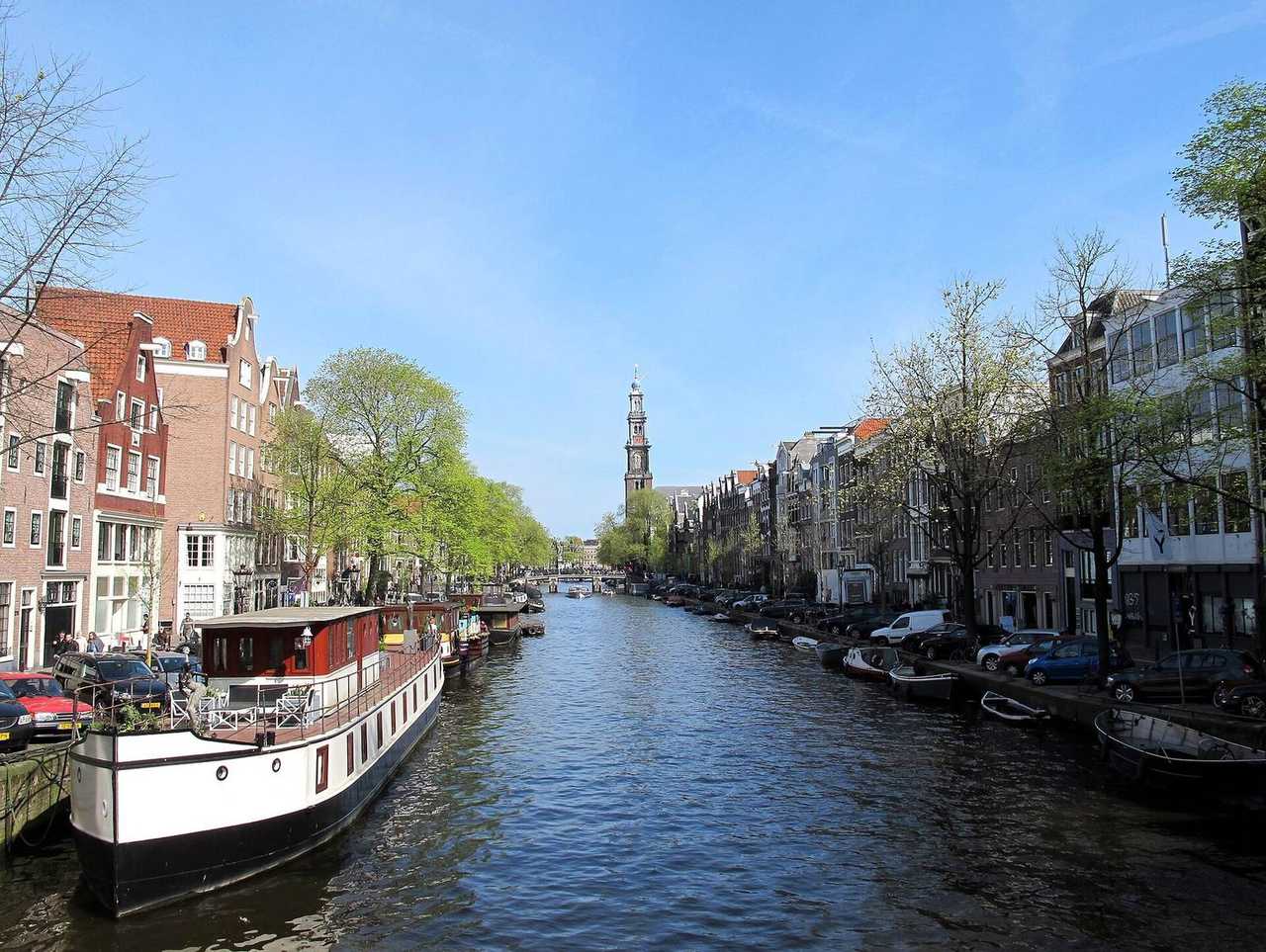 Prinsengracht canal toward Westerkerk, houseboats and gables, day, blue sky