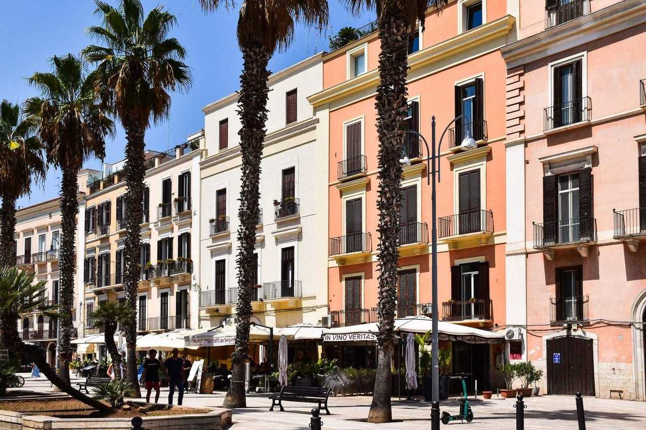 Bari waterfront pastel façades and palm trees with café terraces, day, clear blue sky