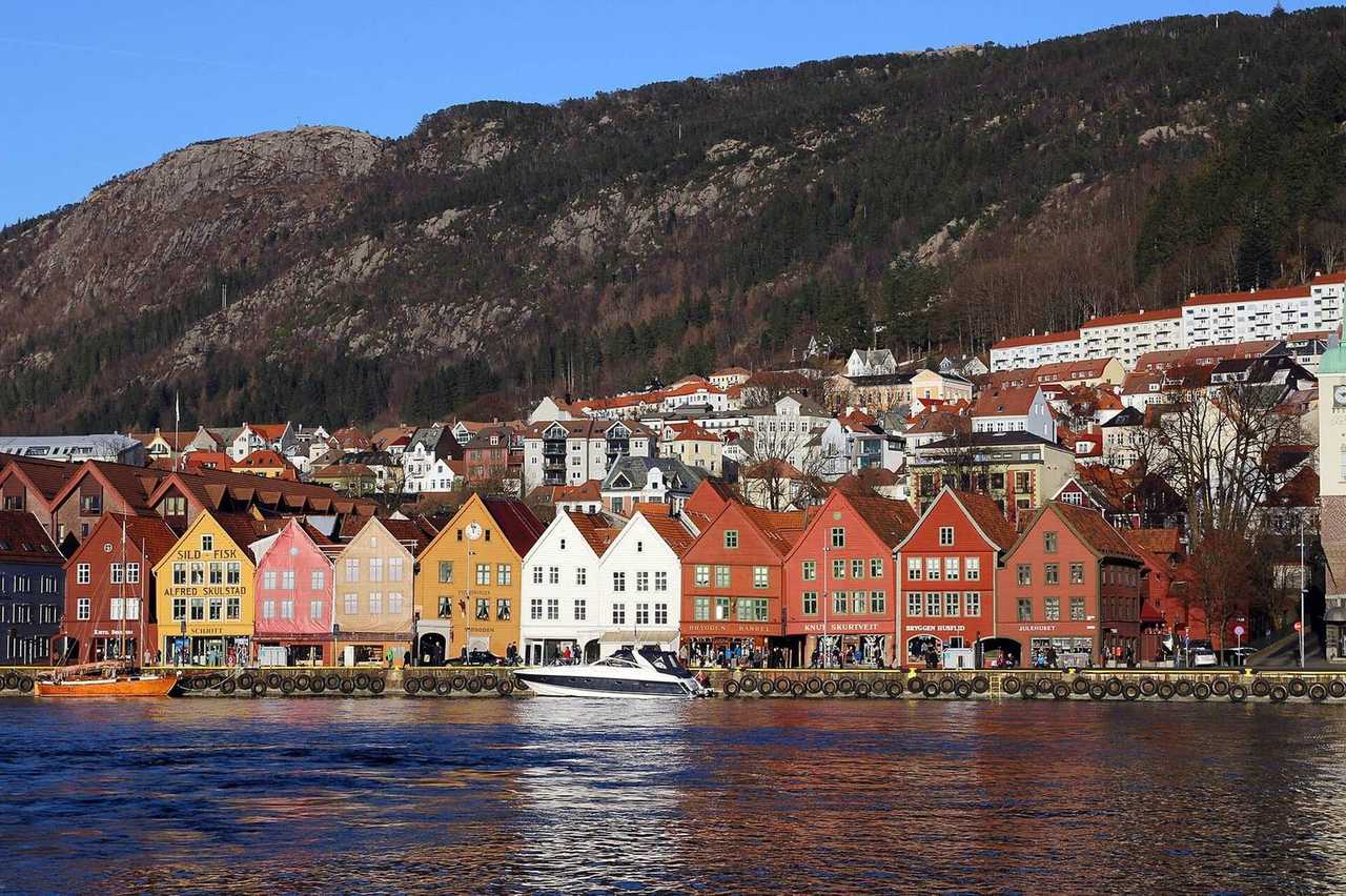 Bryggen Hanseatic wharf from the harbour, colourful gables and mountain, day, blue sky