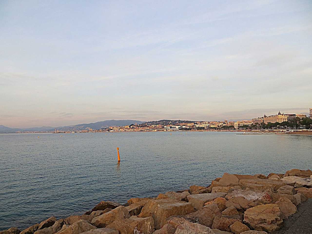 La Croisette / bay skyline from the rocks, late-afternoon pale blue sky, not night