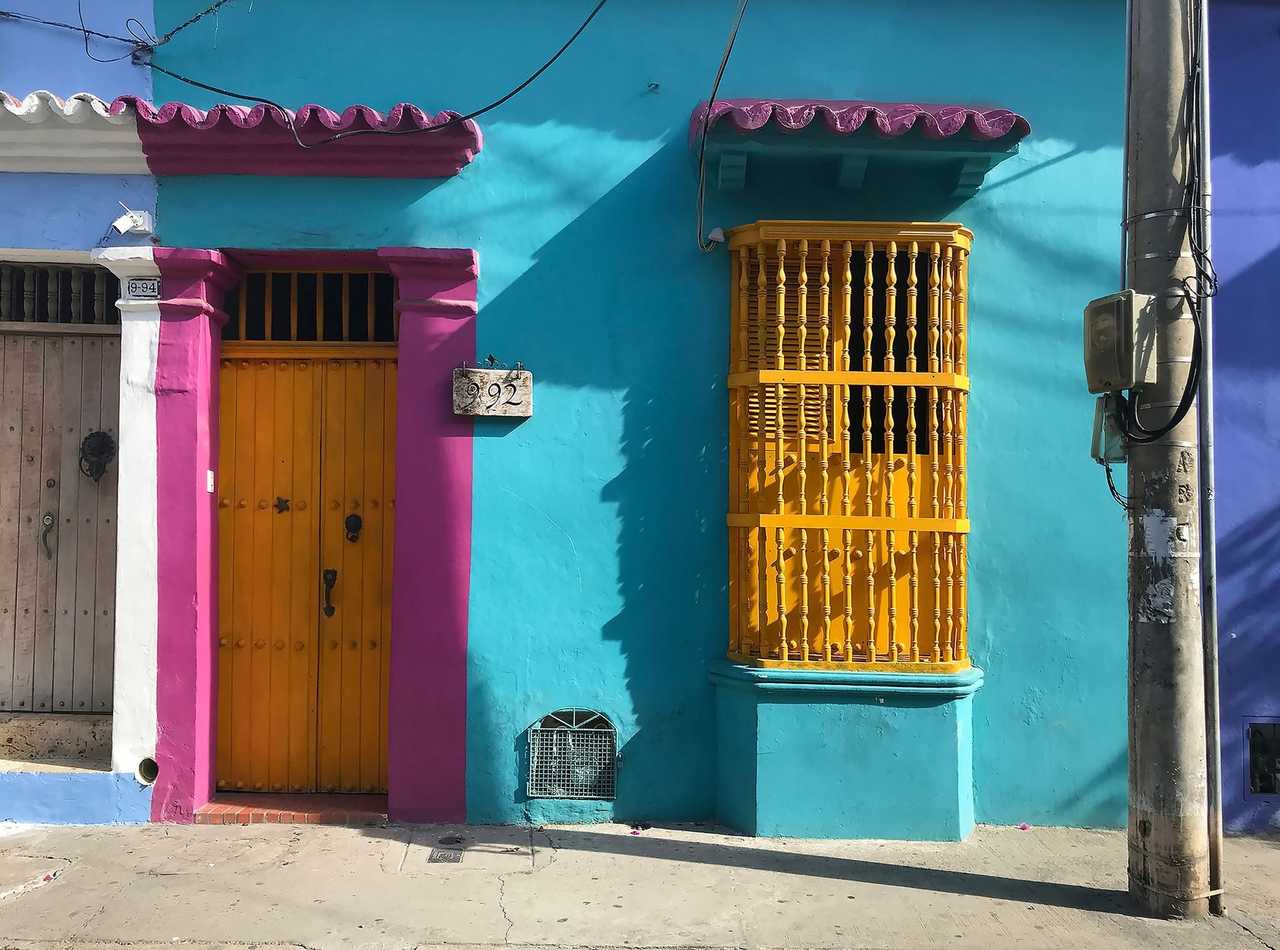 Cartagena colonial cyan façade with yellow reja and magenta trim, sunny day
