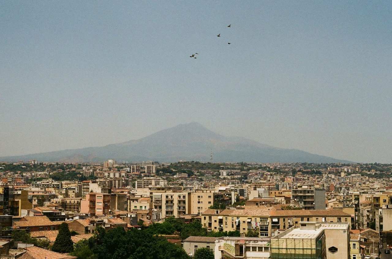Catania rooftops with Mount Etna, day, pale blue sky