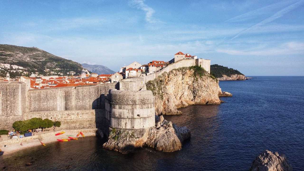 Dubrovnik city walls and red roofs above the Adriatic, day, pale blue sky