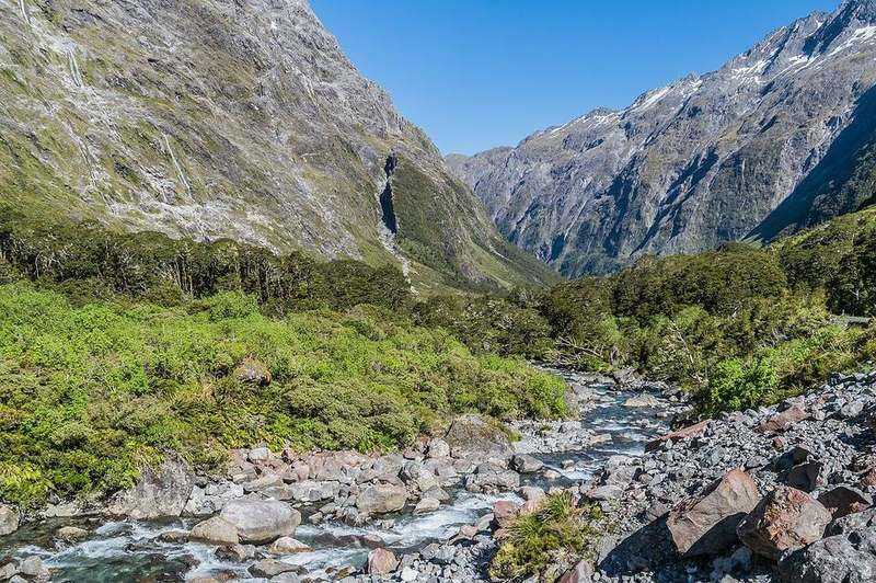 Steep Fiordland sound walls and waterfalls under misty New Zealand rain