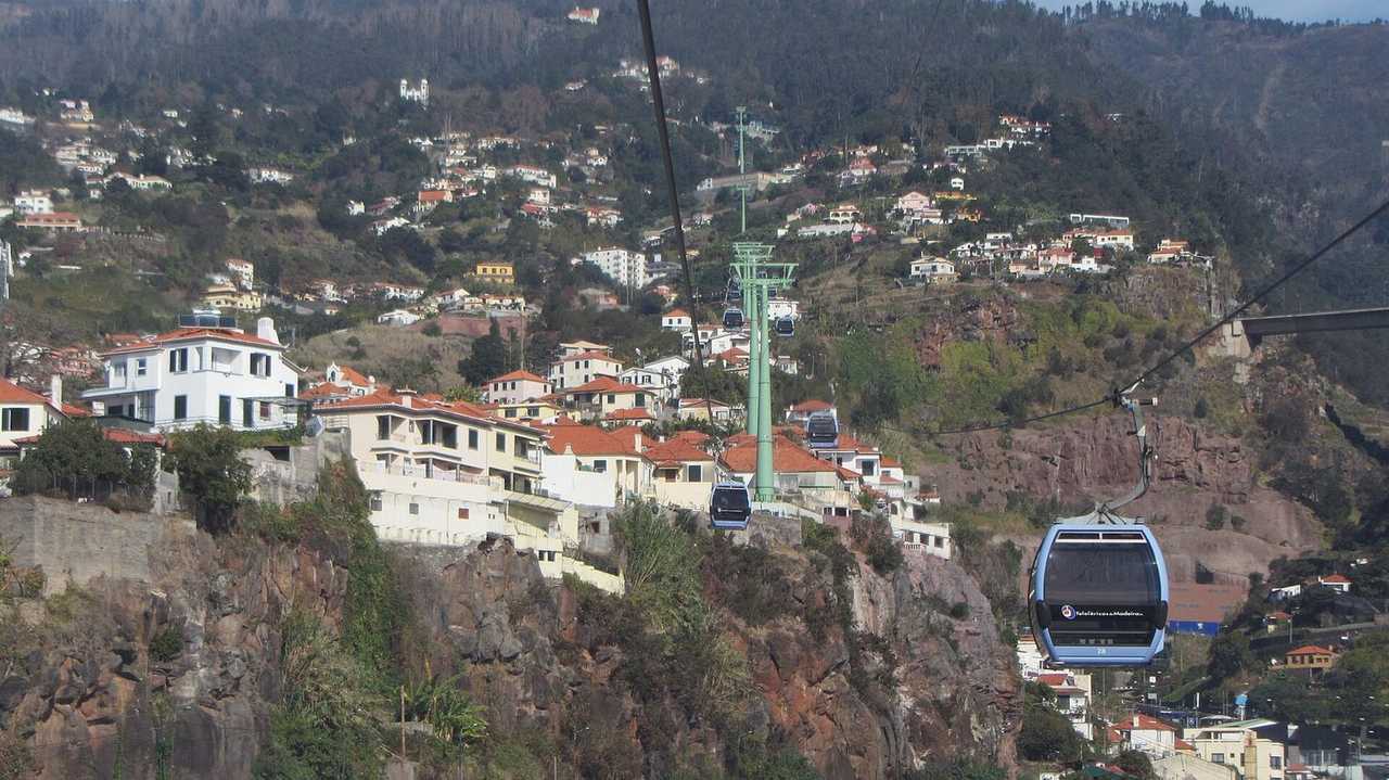 Funchal hillside and Teleférico da Madeira cable cars, day, pale blue sky