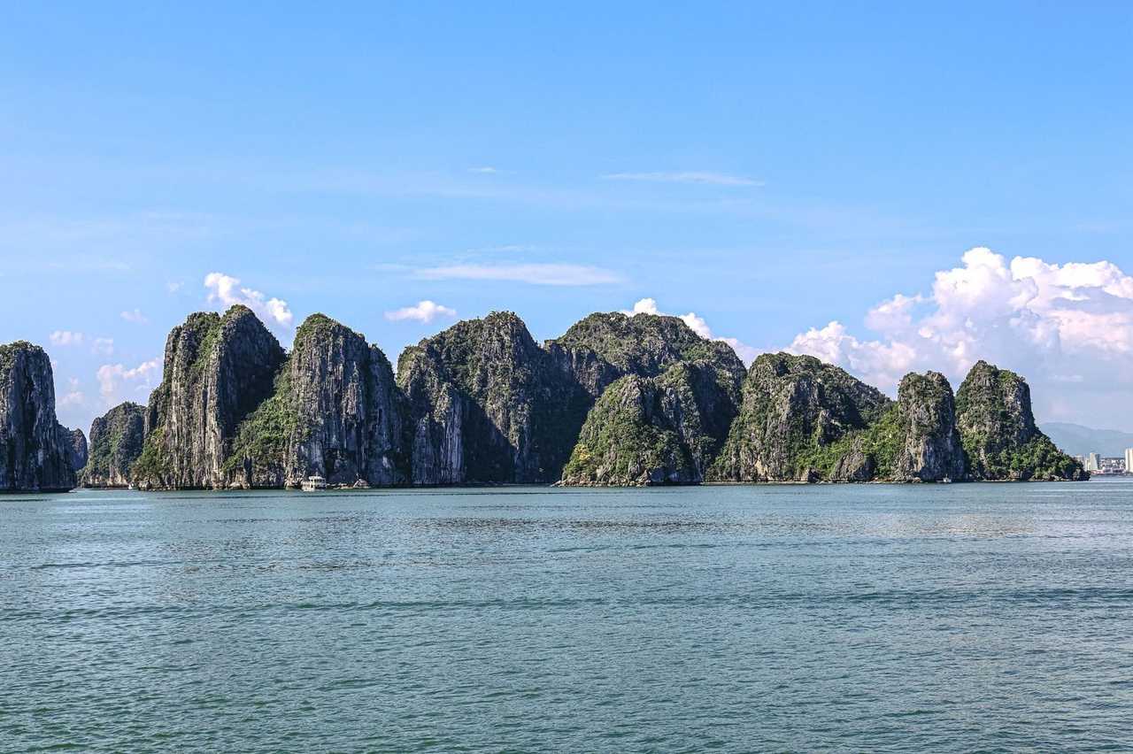 Ha Long Bay limestone karsts and tourist boat, day, clear blue sky