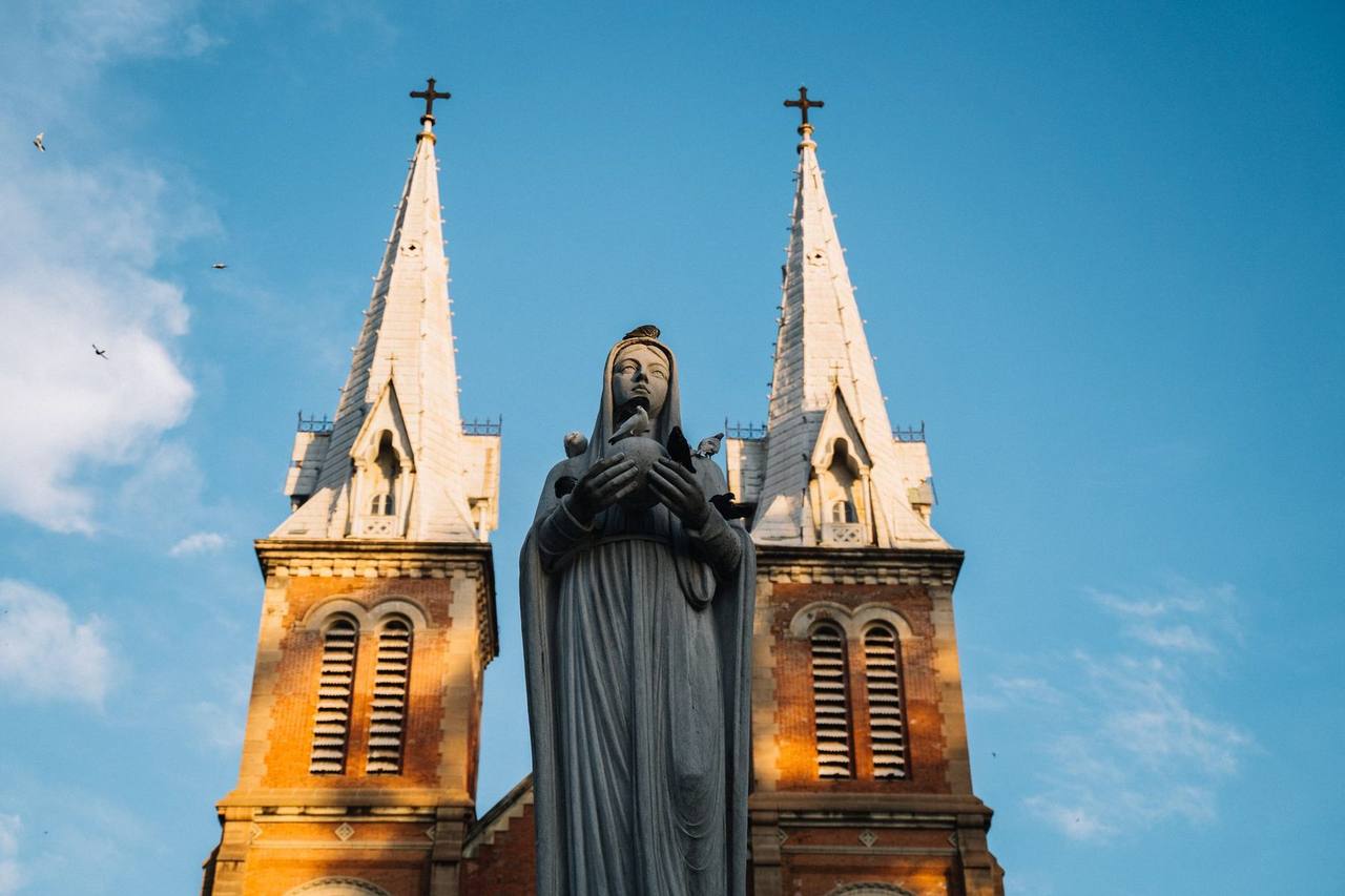 Notre-Dame Cathedral Basilica of Saigon twin towers with Virgin Mary statue, day, blue sky