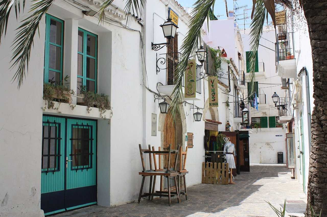 Ibiza Town / Dalt Vila street: whitewashed walls, VINOS DE IBIZA signage incidental, day, sun