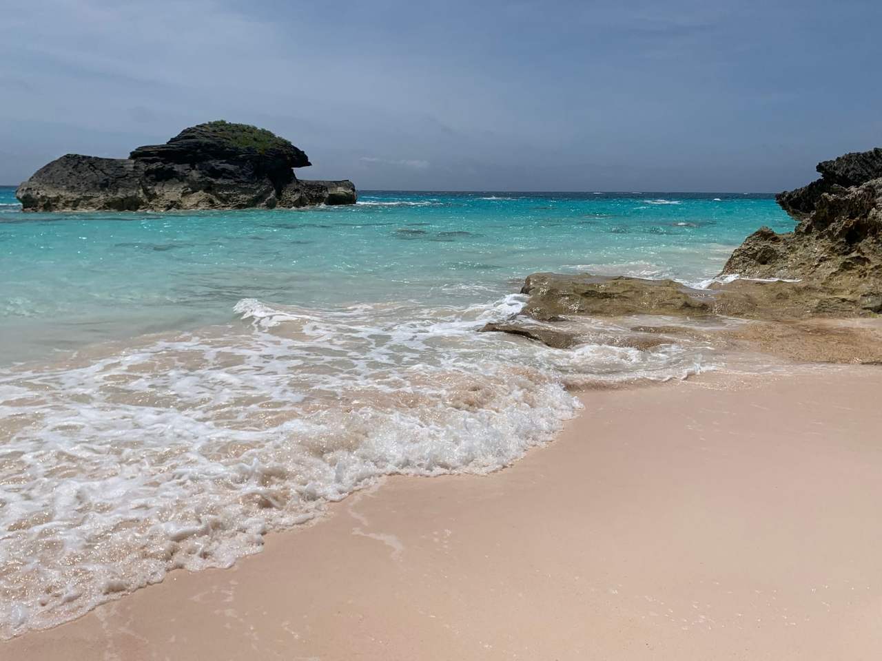 Bermuda pinkish sand cove with limestone rocks and turquoise water, day, blue sky