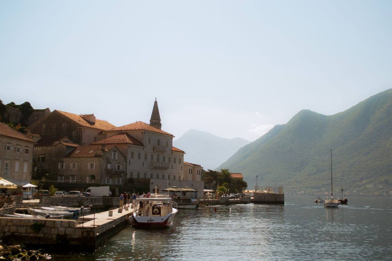 Bay of Kotor / Perast waterfront with mountains, day, pale blue sky