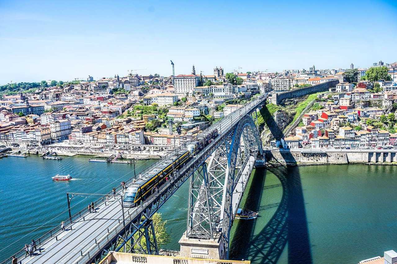 Dom Luís I Bridge upper deck over Douro with Porto hillside, day, solid blue sky