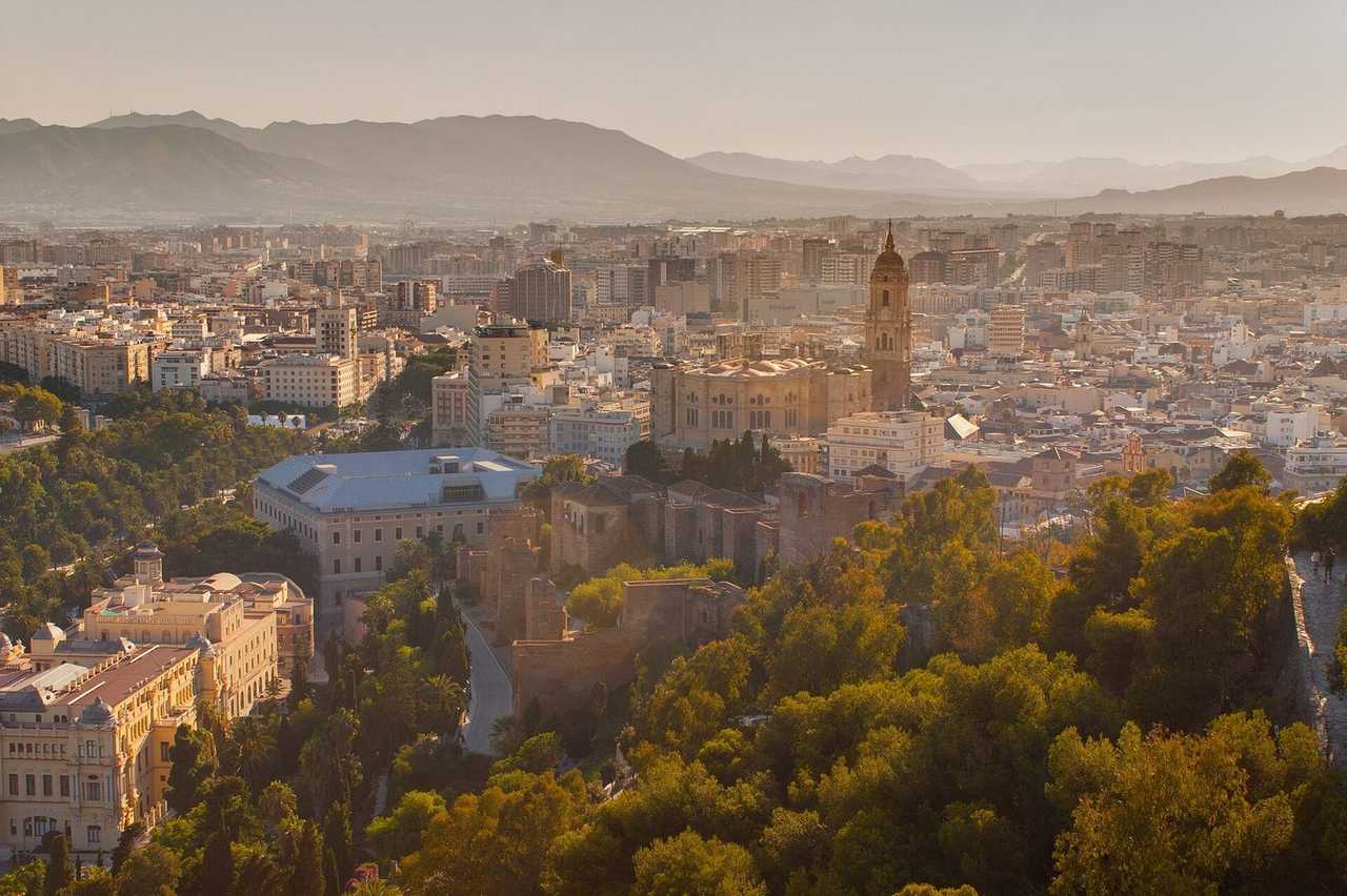 Malaga Cathedral and historic centre from Alcazaba/Gibralfaro, golden daylight, pale blue sky
