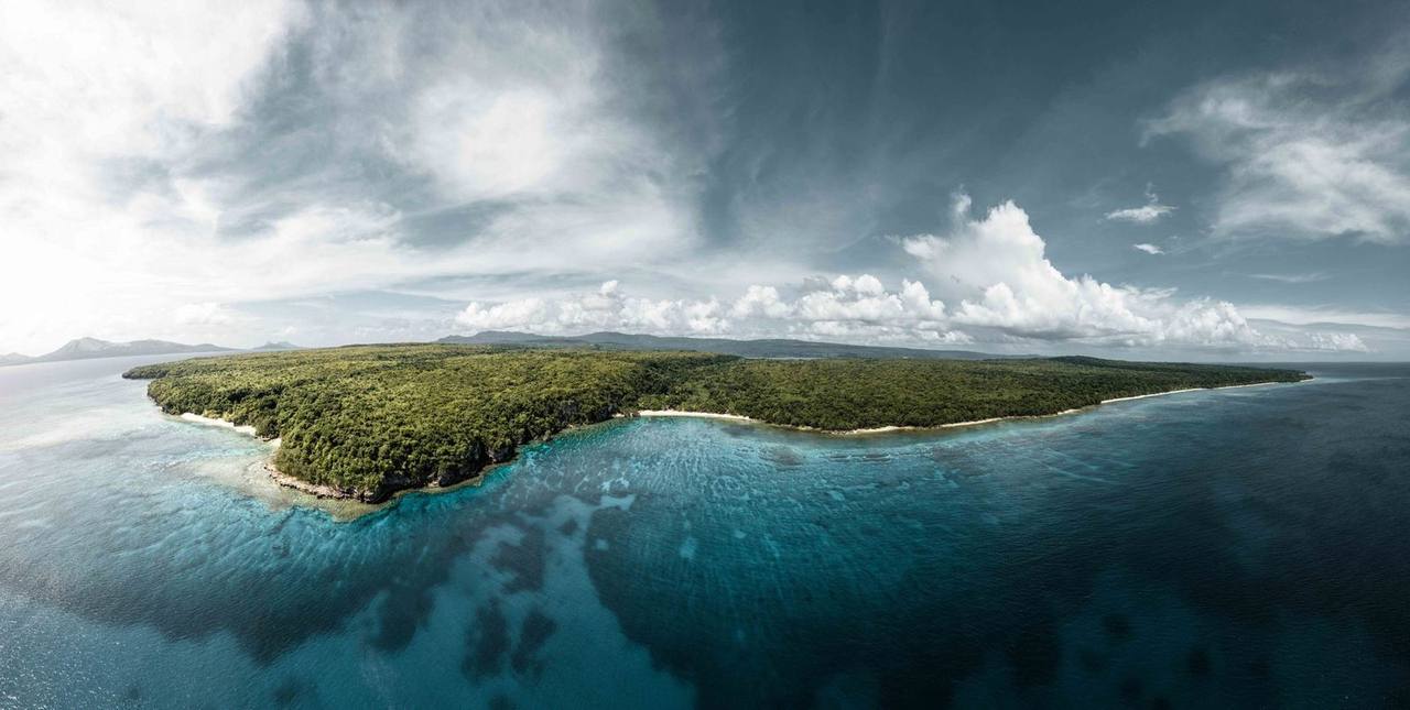 Aerial of lush Vanuatu coastline and turquoise reef shallows (Mystery Island / Aneityum), day, blue sky