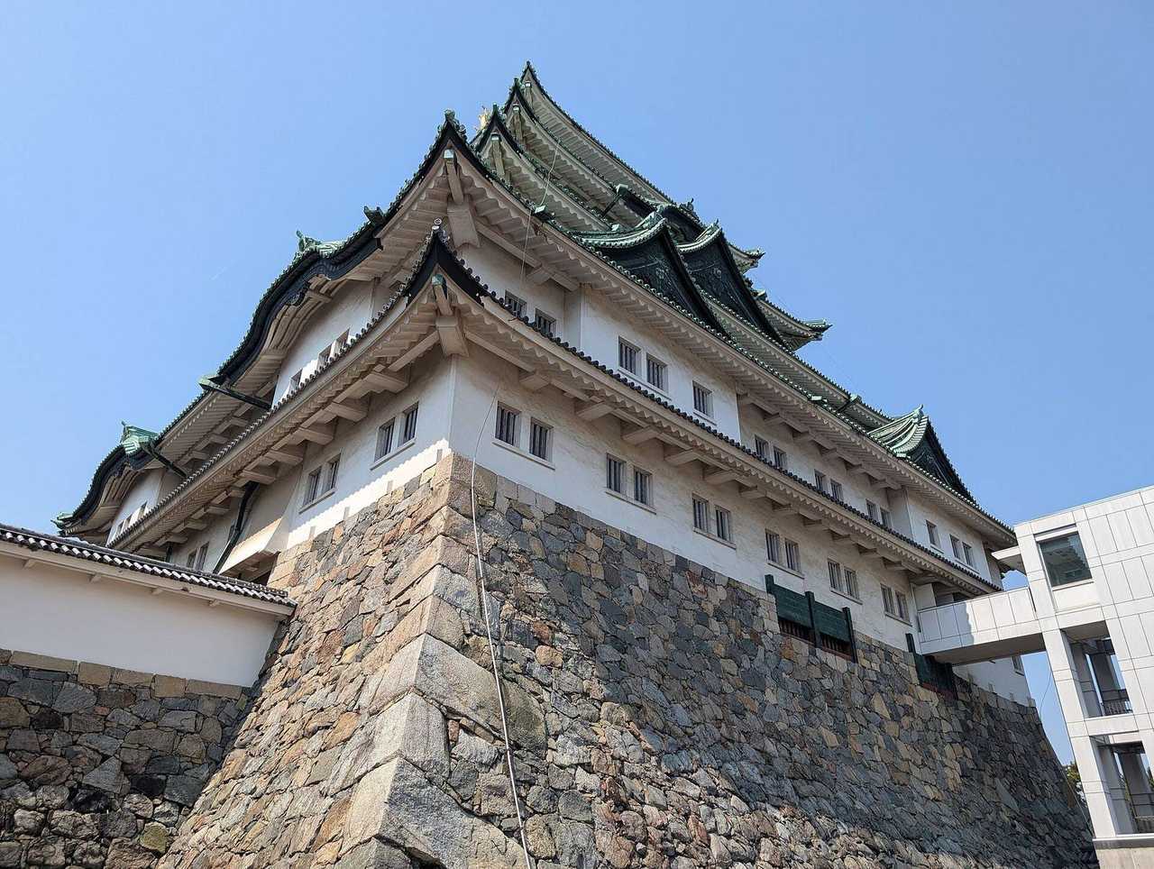 Nagoya Castle keep on ishigaki under solid blue sky, day