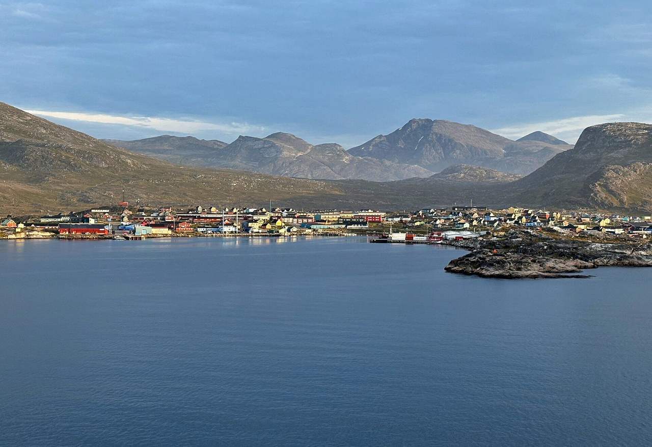 Nanortalik colourful houses under Quassik peaks from the water, day, pale blue sky