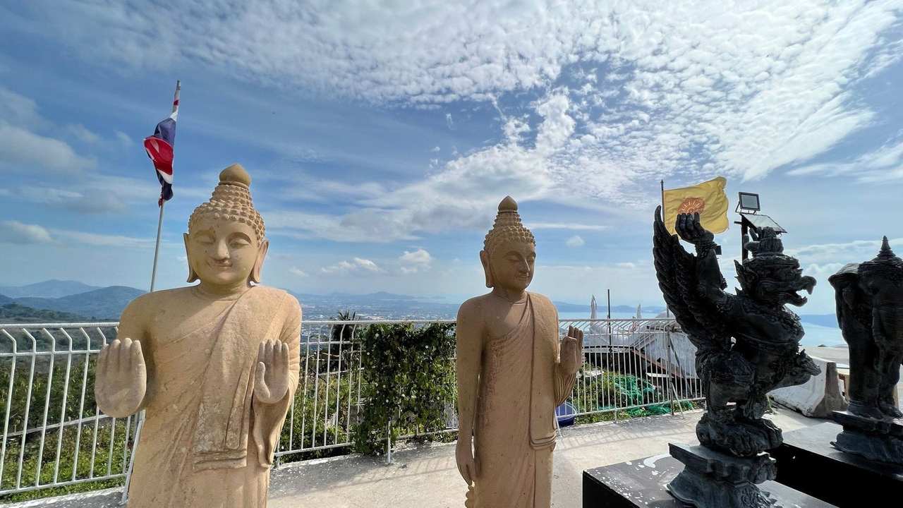Phuket Big Buddha hill viewpoint — Thai flags, Buddha statues, and Chalong Bay panorama, day, blue sky