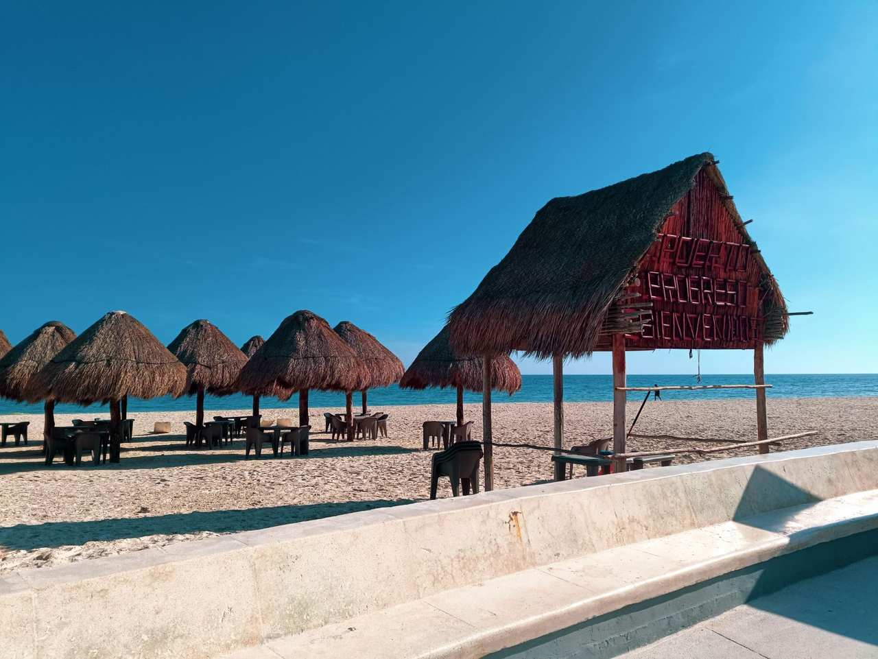 Progreso Beach palapas under clear blue sky, Yucatán; place welcome hut visible, no docks