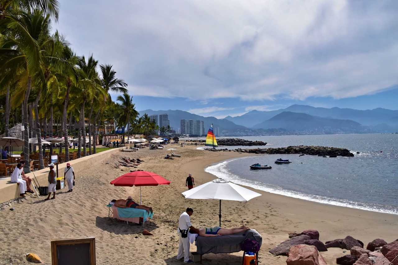 Puerto Vallarta beach with palms and bay mountains, day, blue sky