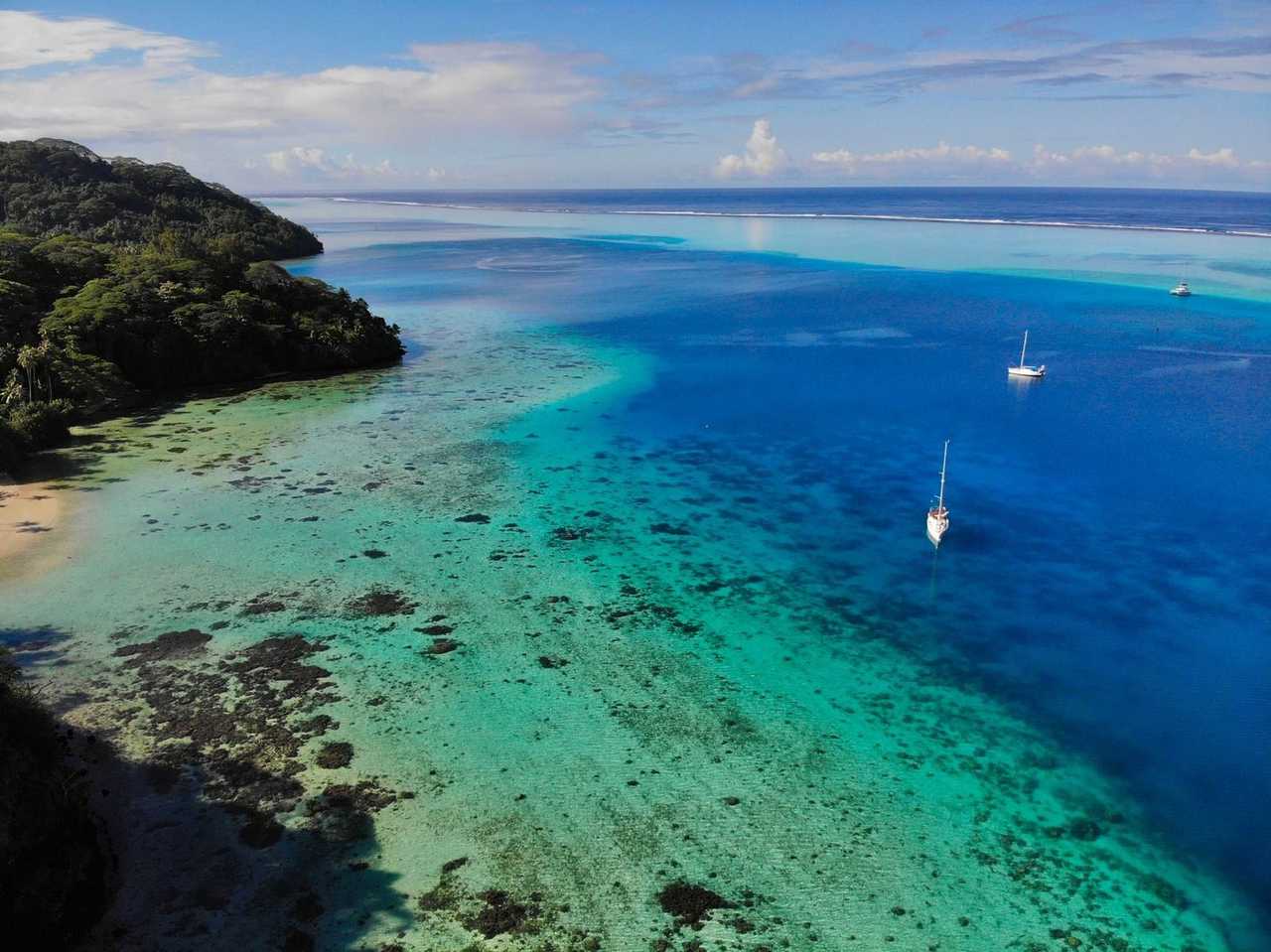 Raiatea-style Society Islands lagoon and forested hillside, day, blue sky