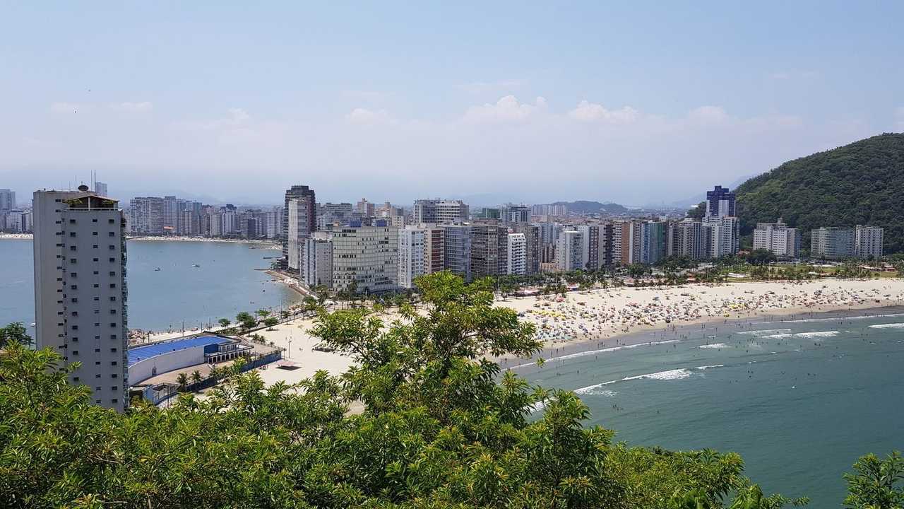 Santos beach crescent and high-rise strip from elevated hill, day, blue sky