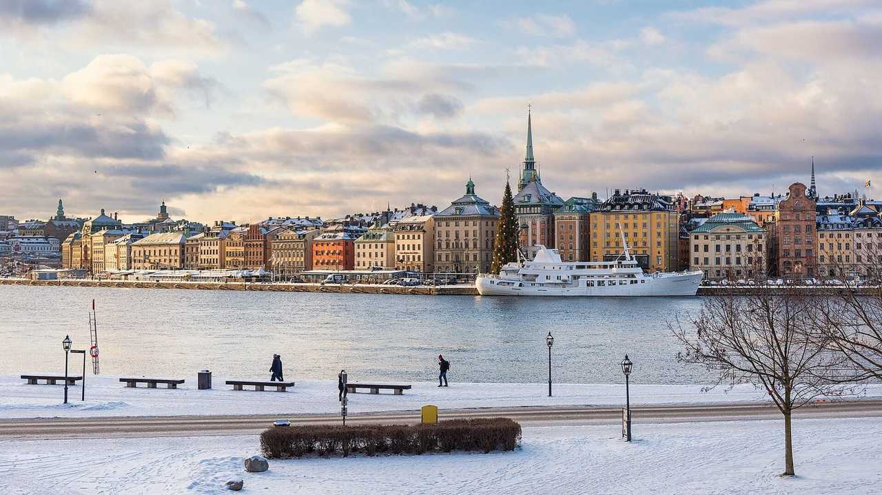 Gamla Stan waterfront from Skeppsholmen: historic ochre facades, church spires, winter snow but bright blue sky