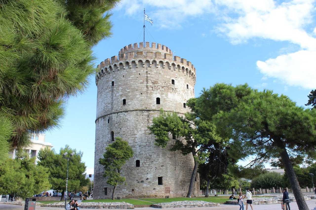 White Tower of Thessaloniki among pines, day, blue sky
