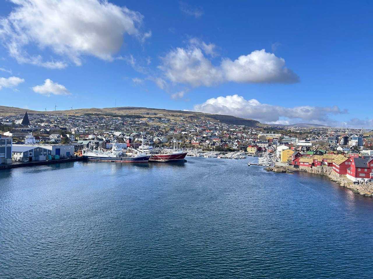 Tórshavn harbour with Tinganes red turf-roof houses identifiable, day, blue sky with cumulus