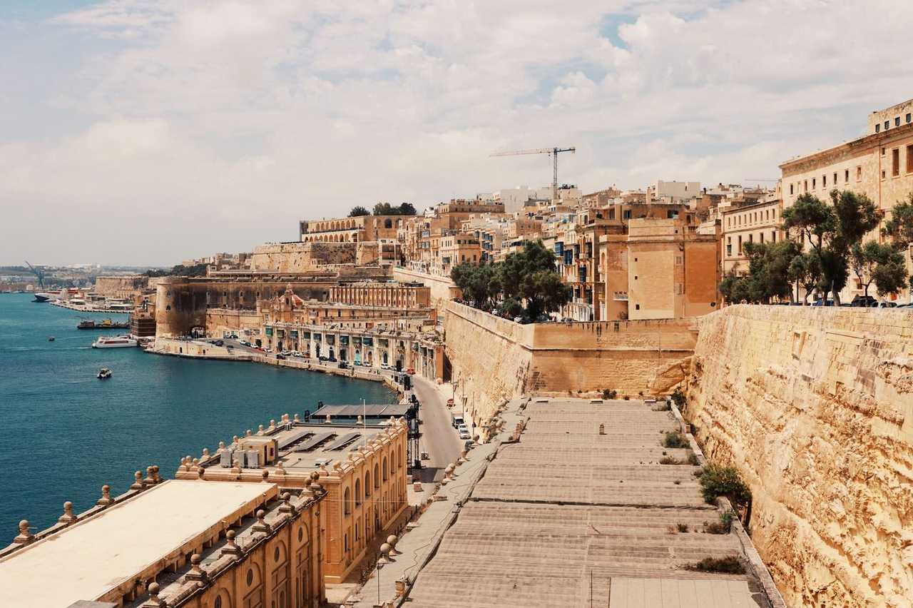 Valletta limestone fortifications and Grand Harbour, day, light blue sky
