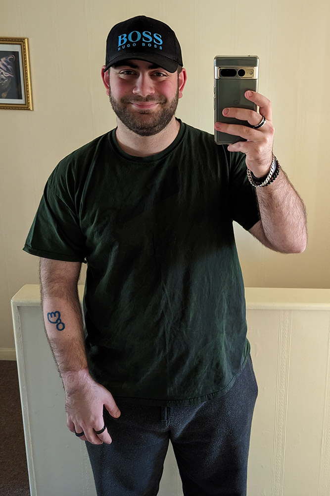 Full body picture of George, showing his arm with tattoo as well as the shaved wrist.