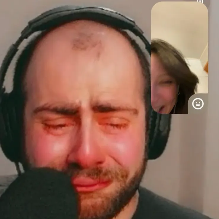 A screenshot of George and his friend on a Snapchat video call, with a crying face filter on George.