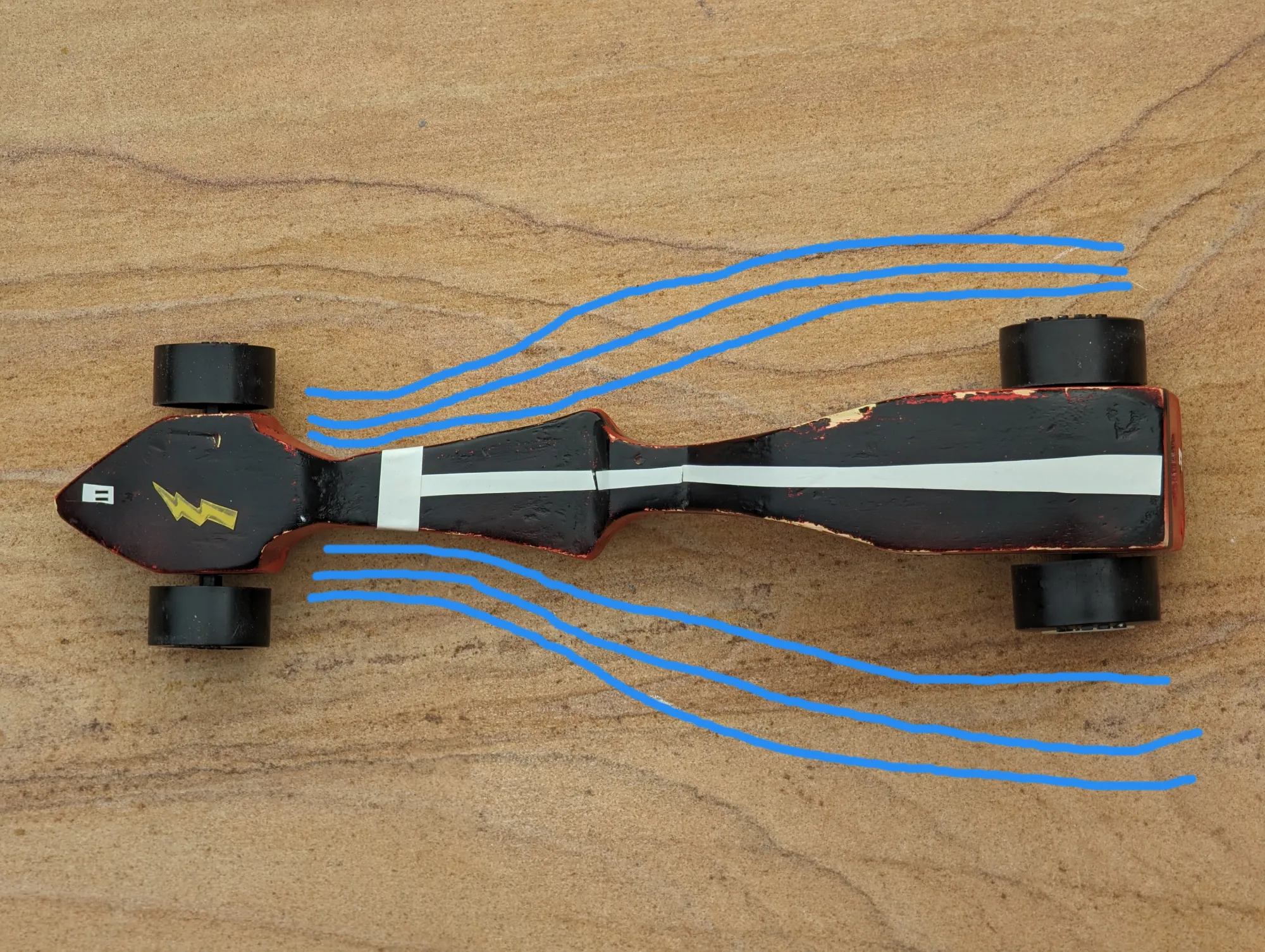 top-down image of a black-painted wooden car with blue lines showing anticipated airflow.