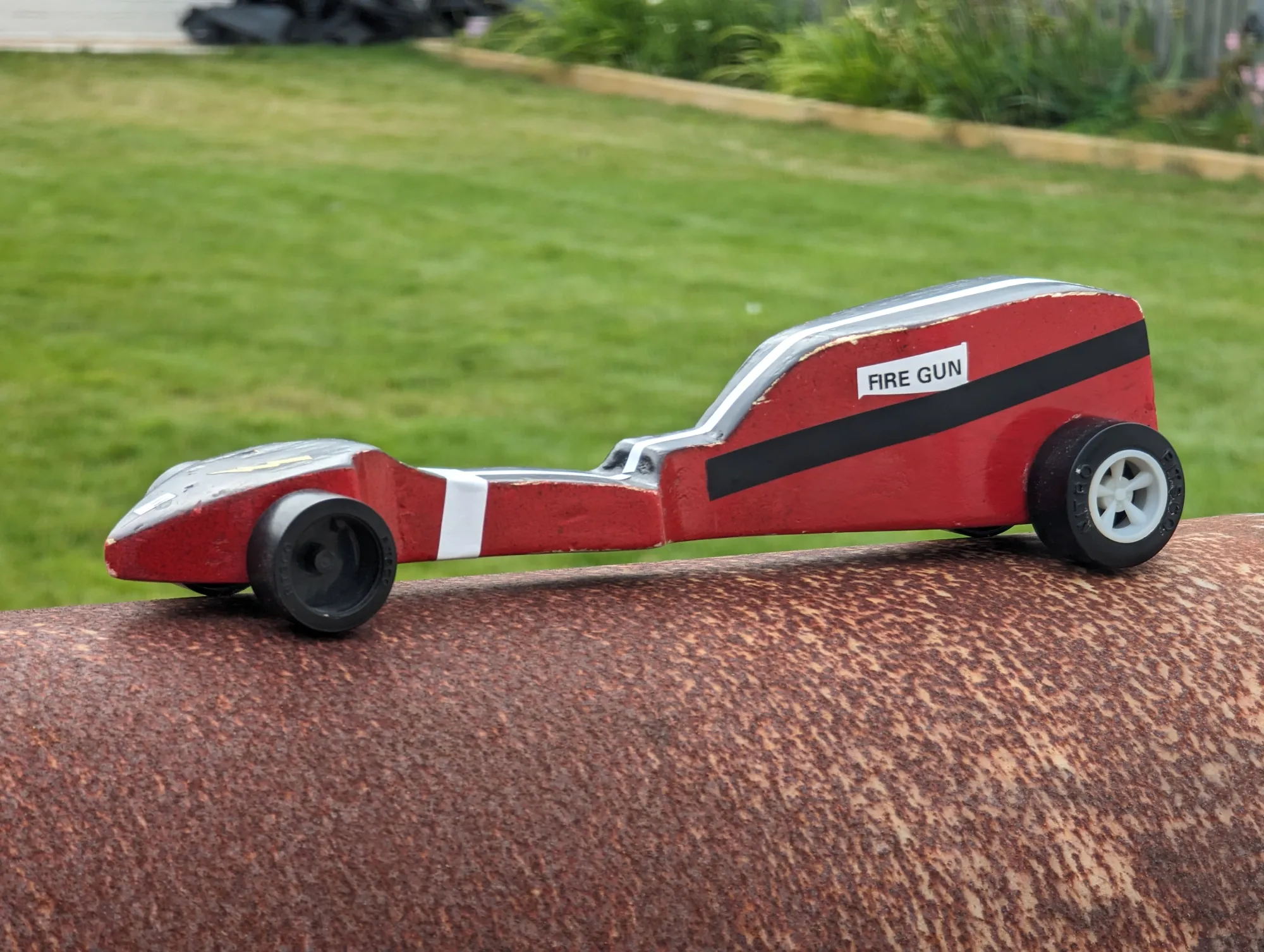 3/4s view of a wooden car with a red side and black top.