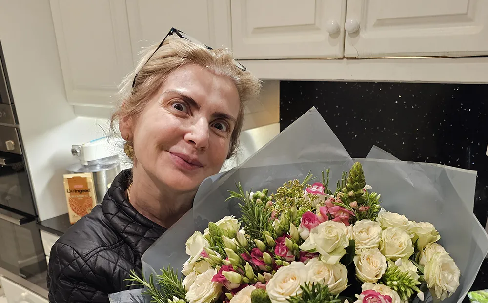Sally smiling and holding a bouquet of flowers.