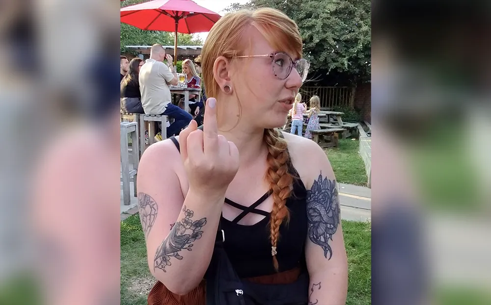 Syd looking away from the camera and showing her middle finger.