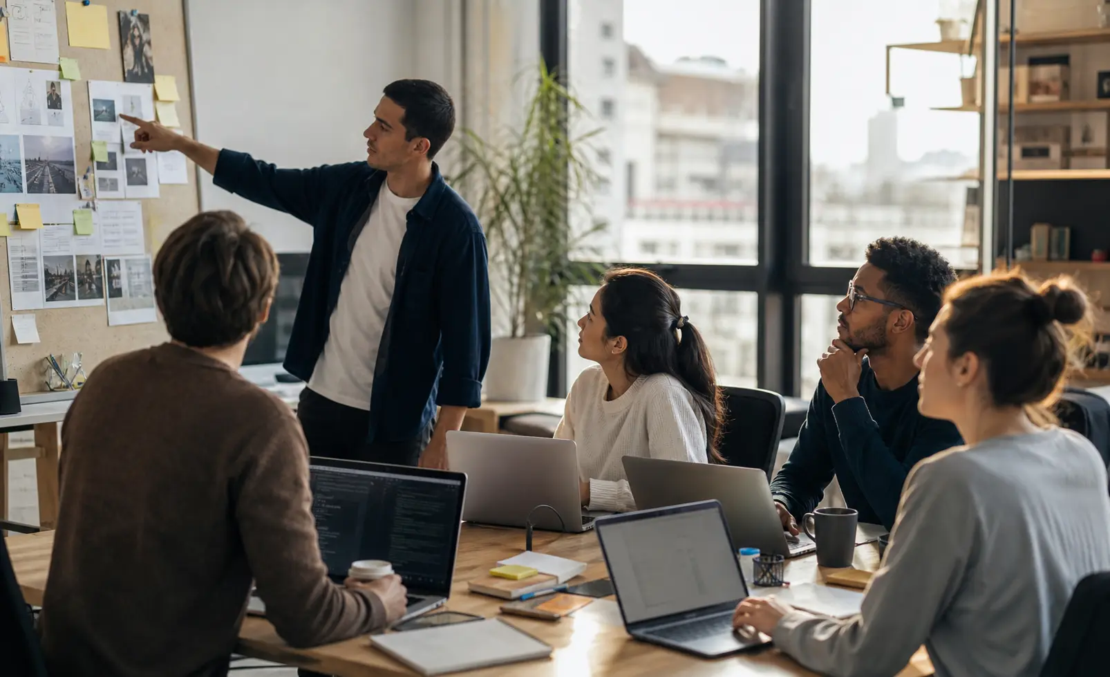 A small cross-functional team coordinates shared work around a project board and several task stations.