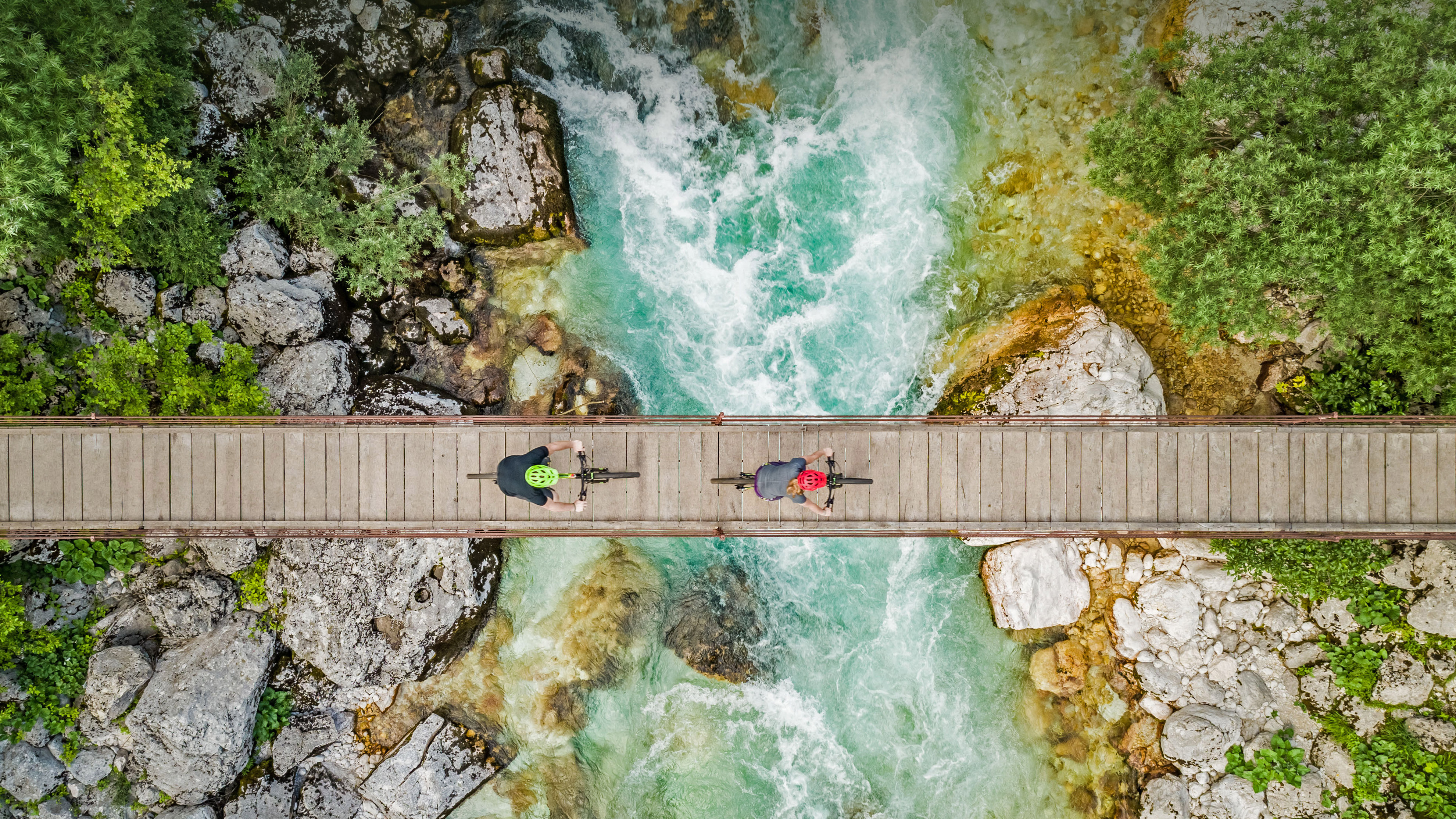 斯洛文尼亚索奇河上的木制吊桥上骑自行车的人的鸟瞰图 (© Amazing Aerial Agency/Offset by Shutterstock)