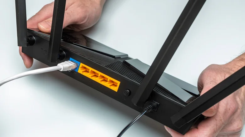 The rear view of a gaming router, showing an Ethernet cable connected to the WAN port, along with four spare ports.