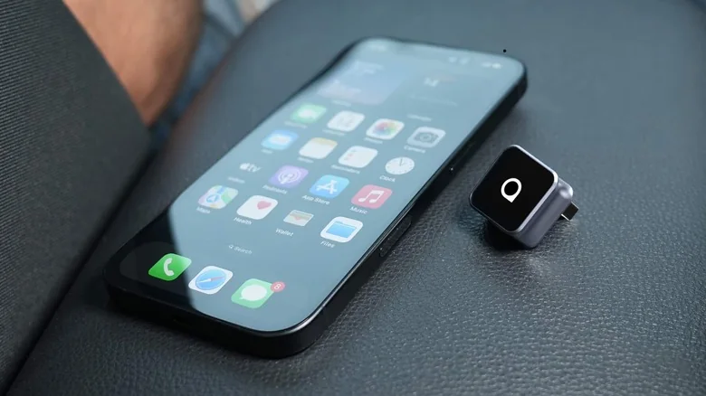 An iPhone next to an Ottocast wireless CarPlay adapter.