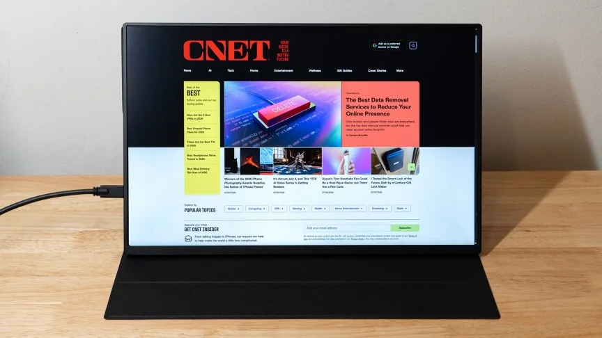 The Uperfect BE16CU portable monitor on a wood table showing the CNET homepage.