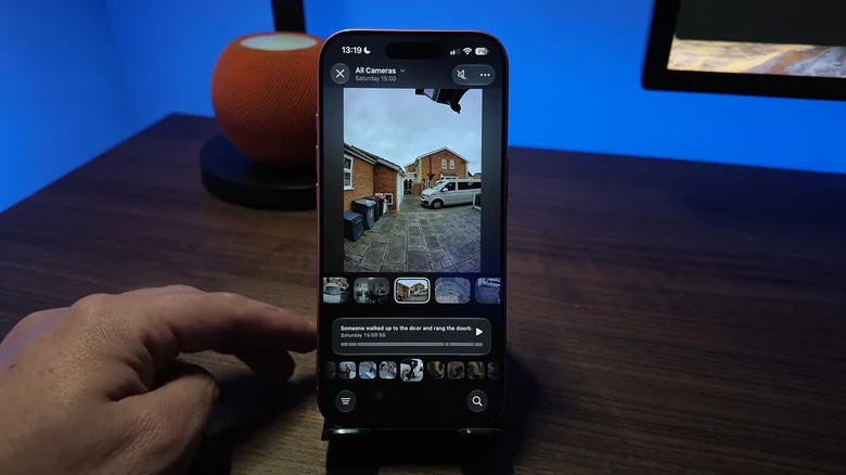 Apple's Home app shows a video of a driveway behind a brown house, where a van pulls up and an AI video description states that someone is about to walk to the front door.