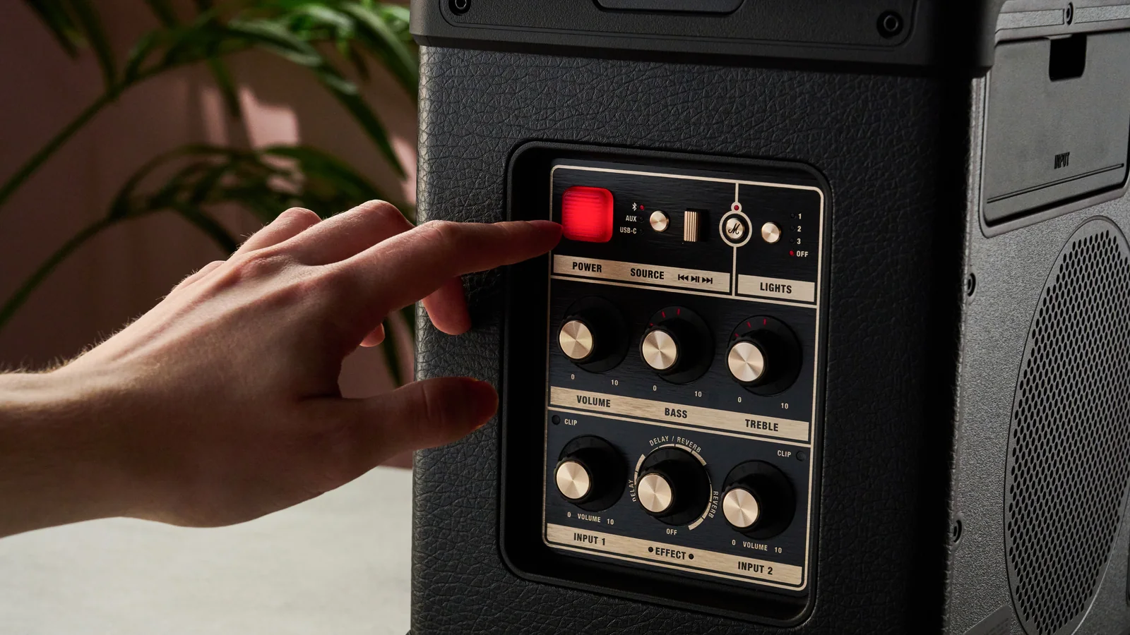 Man pressing the power button on the Marshall Bromley 150