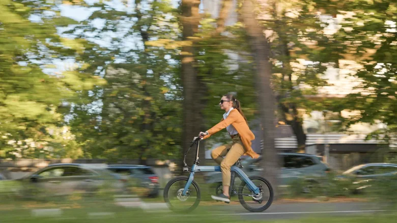Somebody riding a folding electric e-bike through a park.