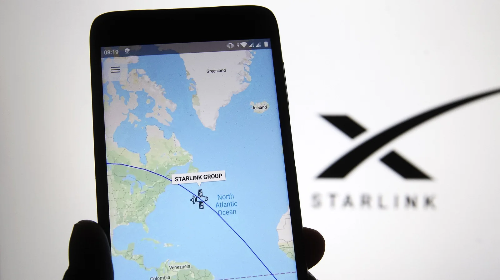 Starlink tracker on phone with Starlink logo in background