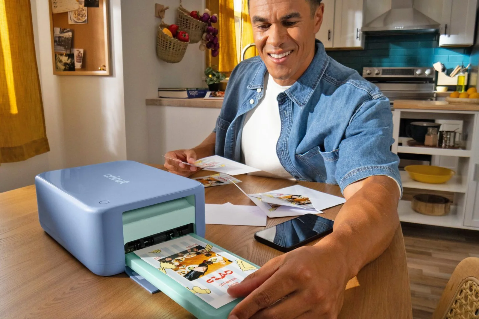 A person removes a print from the Cricut StickerPix Print plus Cut crafting machine being used on a kitchen table.