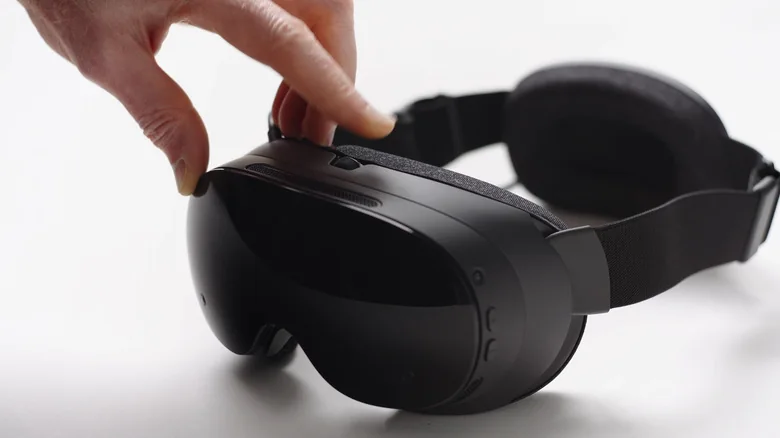 Closeup of the Steam Frame VR headset, with a person's hand touching it.